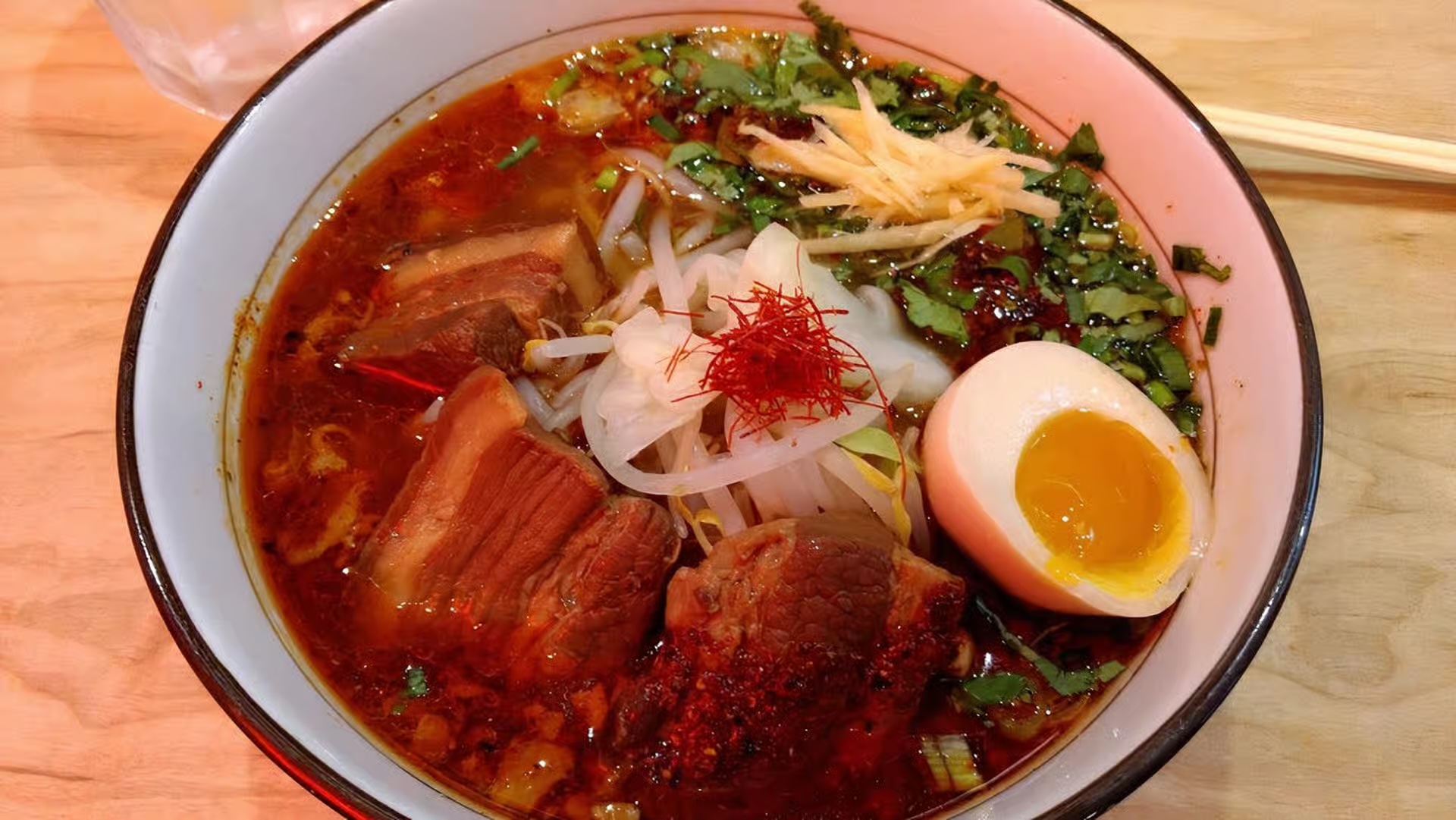 Spicy Ginger Stamina Ramen with braised pork belly, soft-boiled egg, bean sprouts, and chili threads
